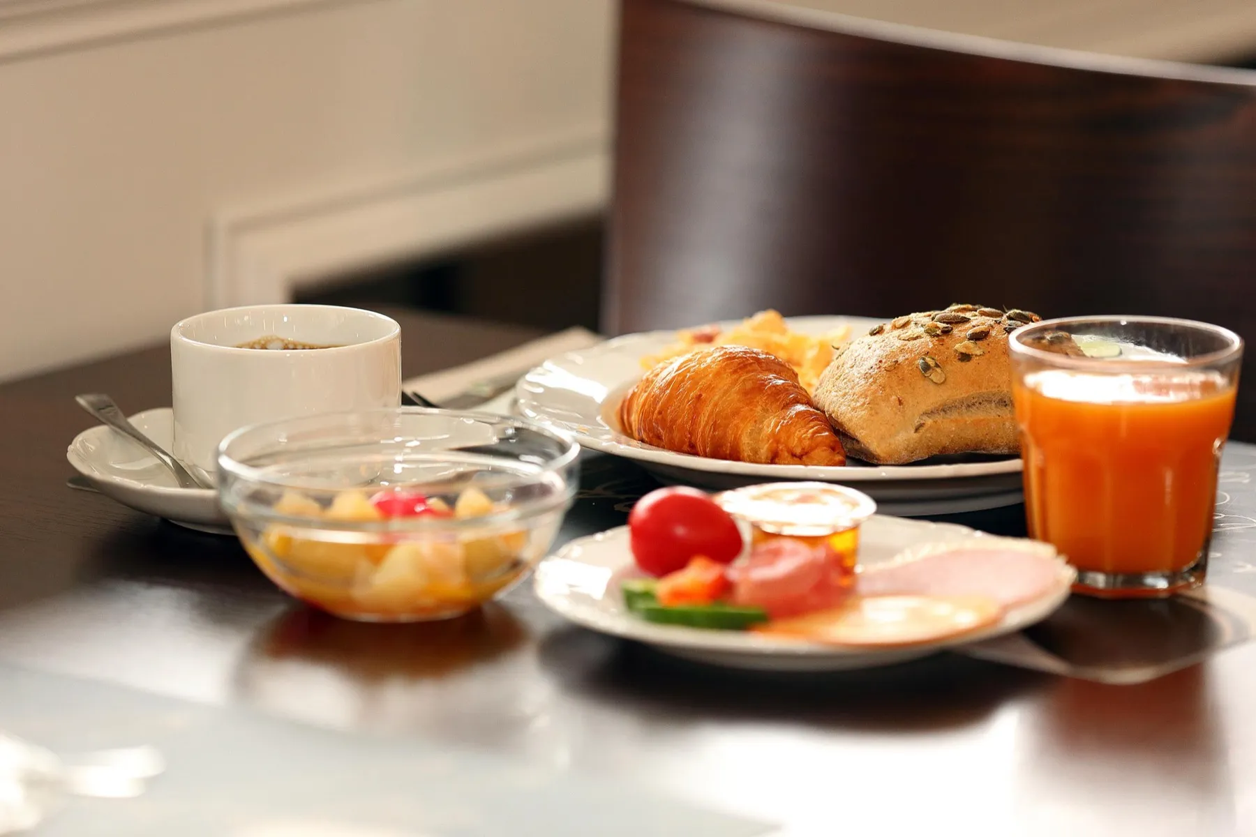 Gedeckter Frühstückstisch mit Croissant, Obst und Orangensaft