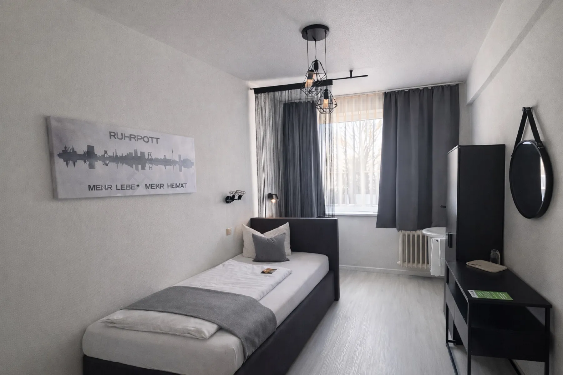 Einzelzimmer mit Waschgelegenheit, Bett und Schreibtisch